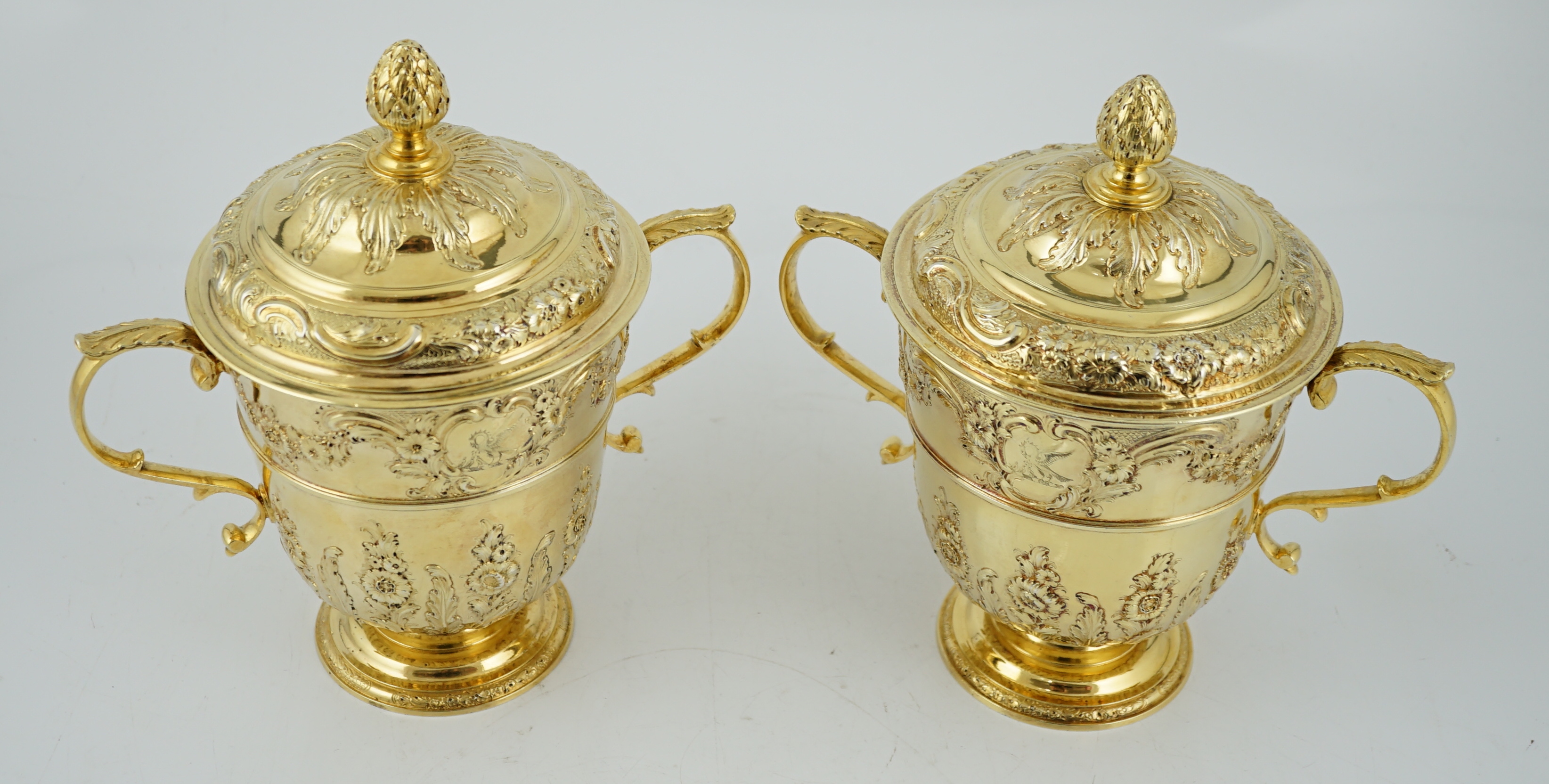 Benacre Hall, Suffolk. A good pair of George II embossed silver gilt two handled pedestal cups and covers, by Benjamin Gignac